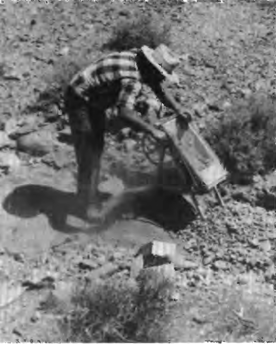 A prospector operating a small hand-operated dry washer in an arroyo bottom, photographed for USGS Professional Paper 1361